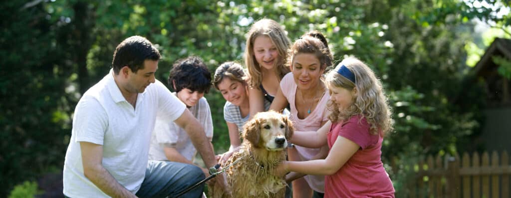 family outdoors, washing their door and laughing